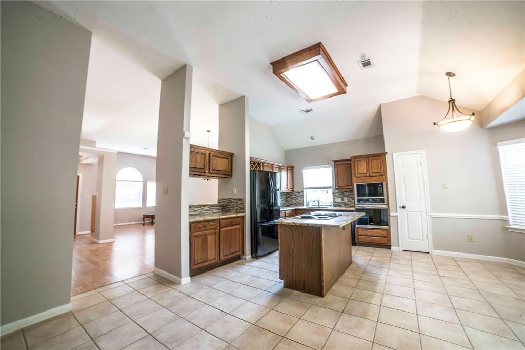 a kitchen with granite countertop a refrigerator and a stove top oven