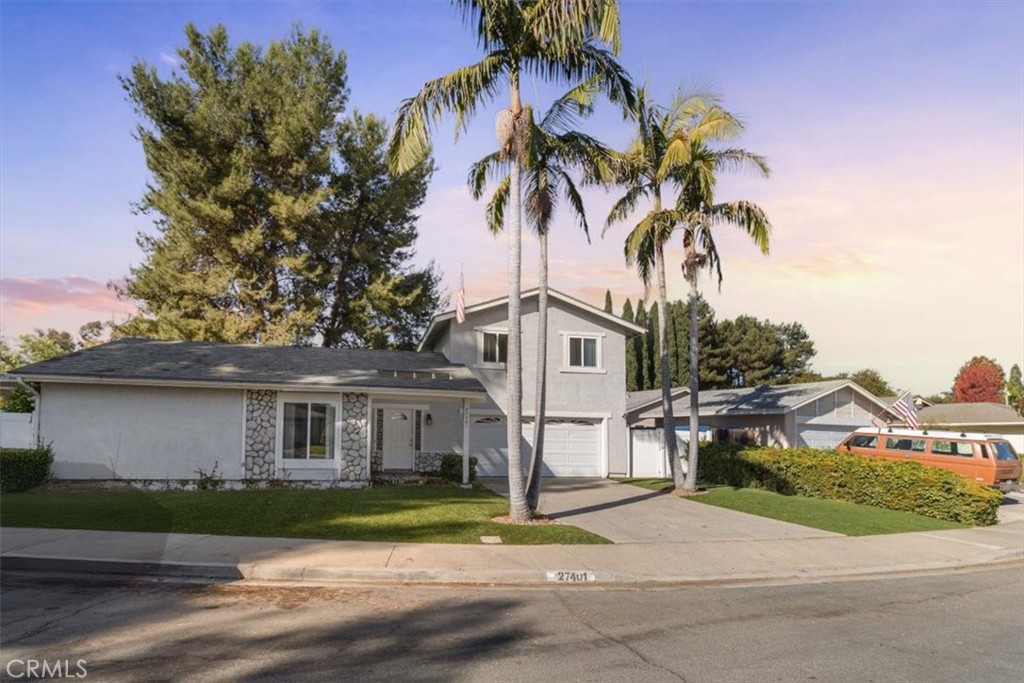 a front view of a house with a garden and trees