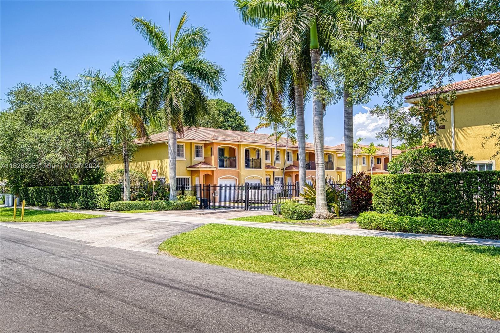 front view of a house with a yard and palm trees