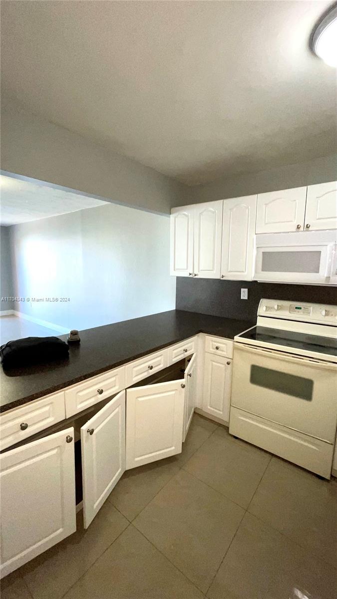 a kitchen with granite countertop white cabinets and white appliances