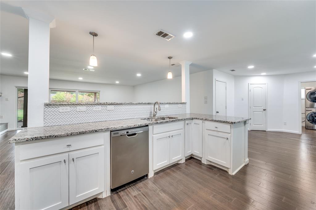 a large kitchen with granite countertop a white stove top oven and white cabinets