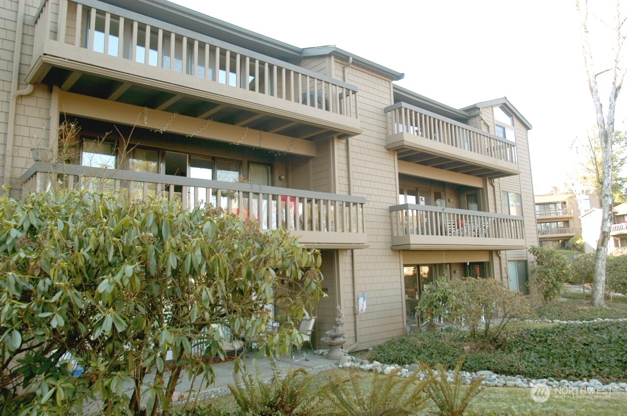 a front view of a building with balcony and trees