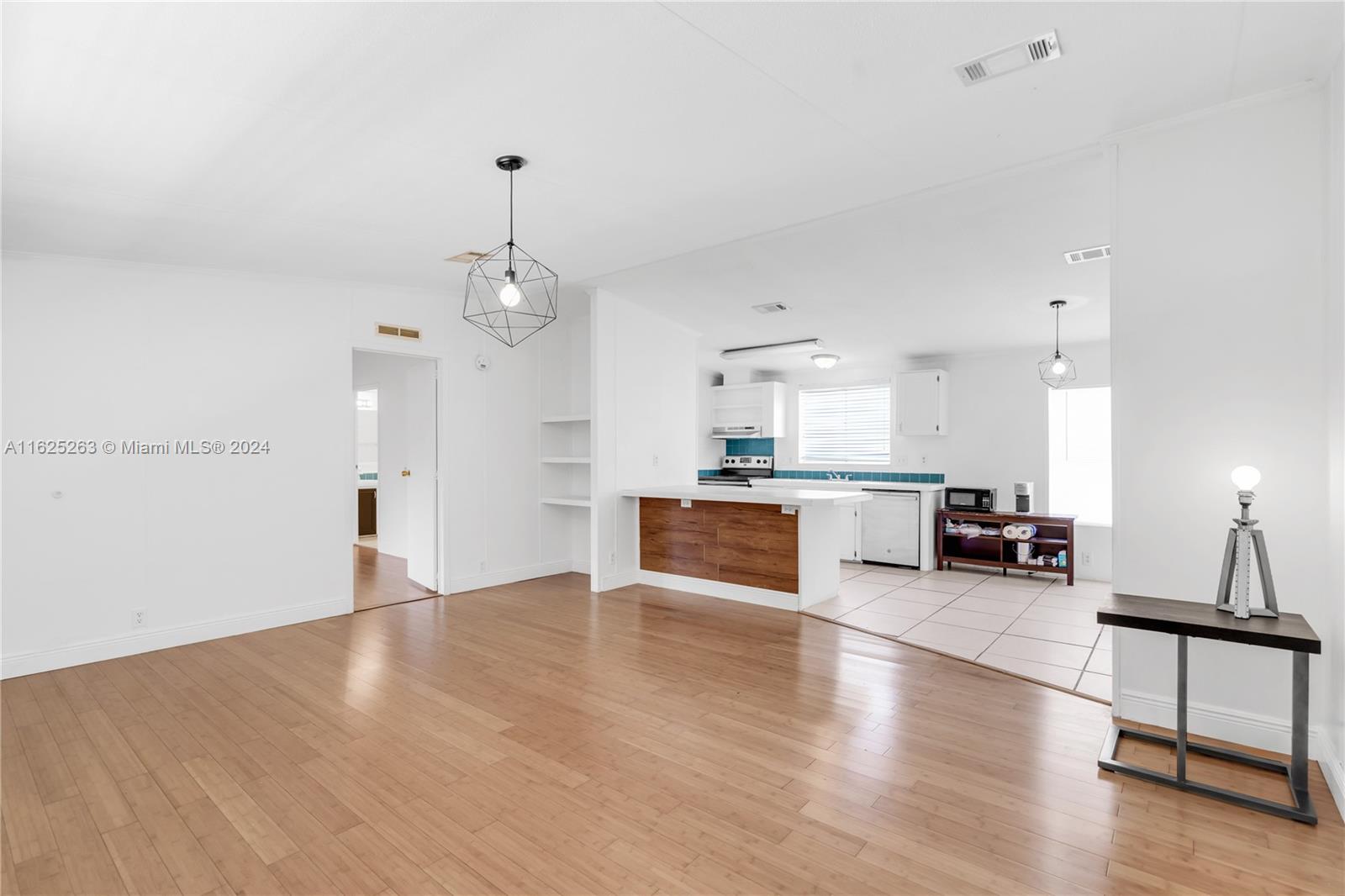 a view of a living room and kitchen with furniture and wooden floor