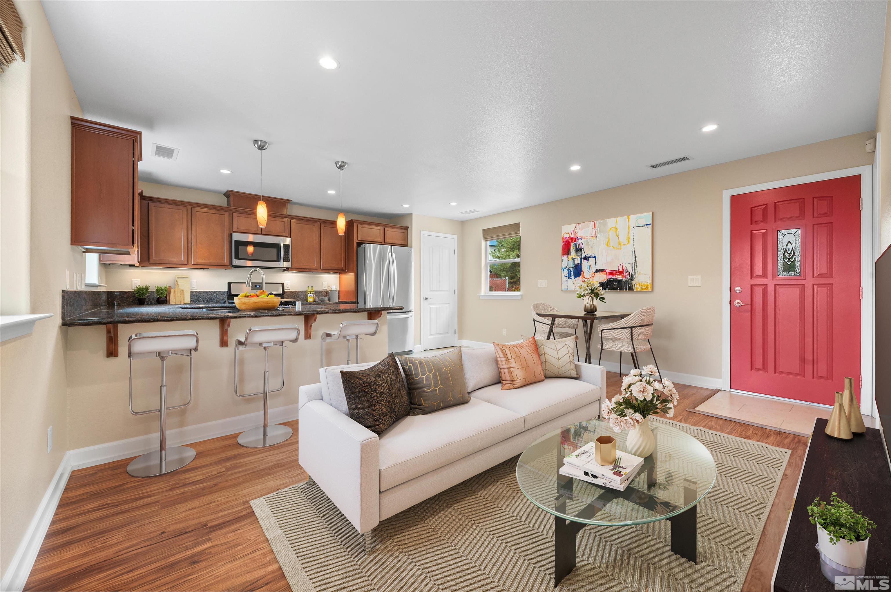 a living room with stainless steel appliances furniture a rug and a kitchen view