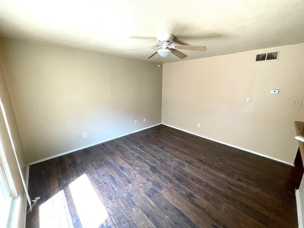 an empty room with wooden floor fan and windows