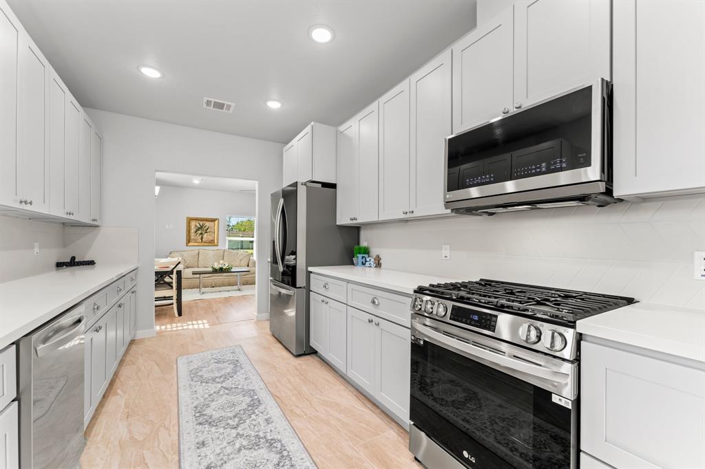 a kitchen with stainless steel appliances a stove a microwave a sink and cabinets