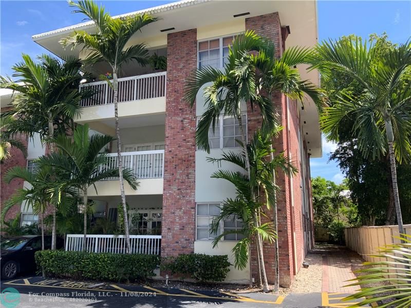 a view of a palm trees front of house with wooden fence