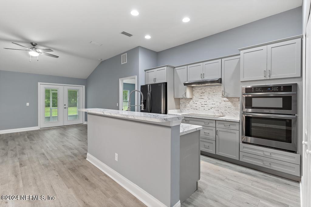 a kitchen with kitchen island granite countertop a stove cabinets and wooden floor