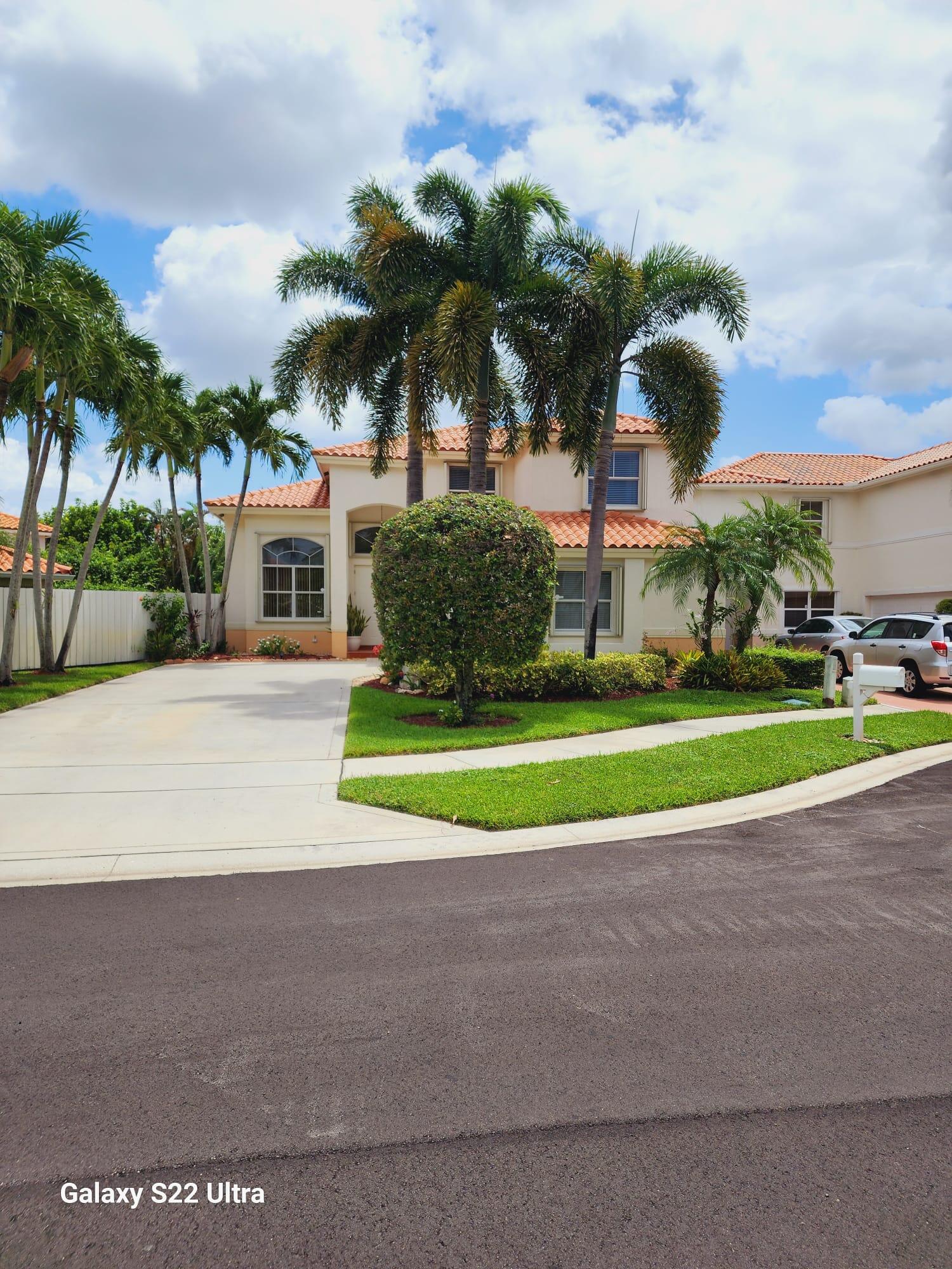 a view of a house with a big yard and palm trees