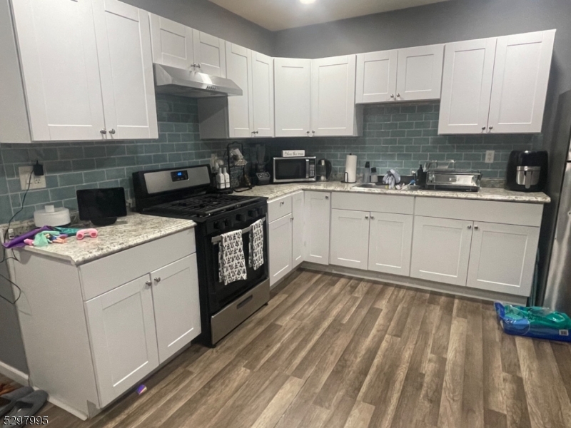 a kitchen with granite countertop a stove sink and cabinets