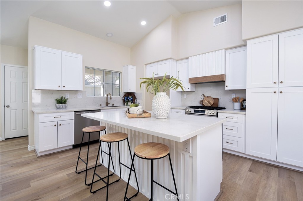 a kitchen with stainless steel appliances a table chairs refrigerator and cabinets