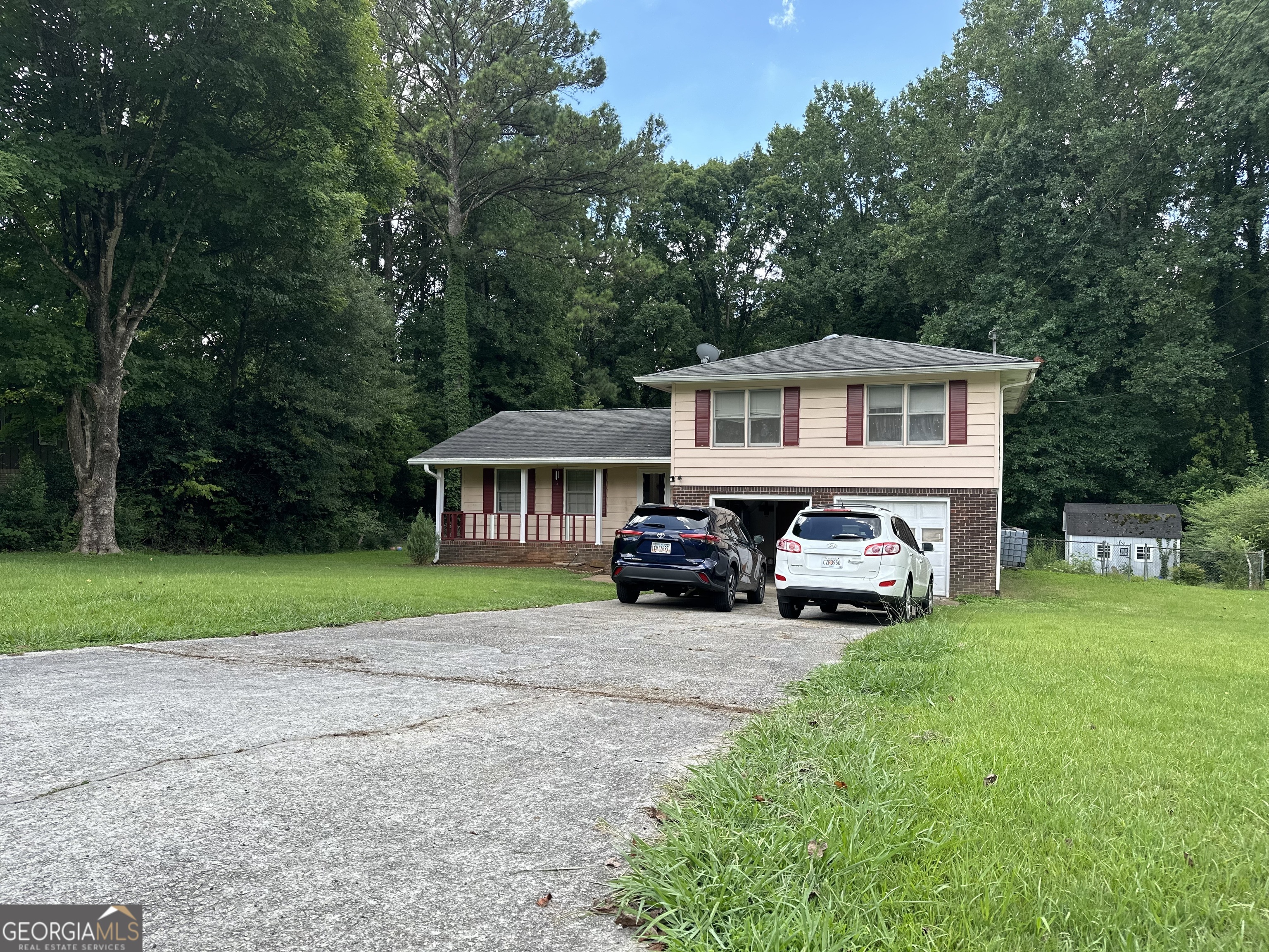 a view of a house with a yard and large trees