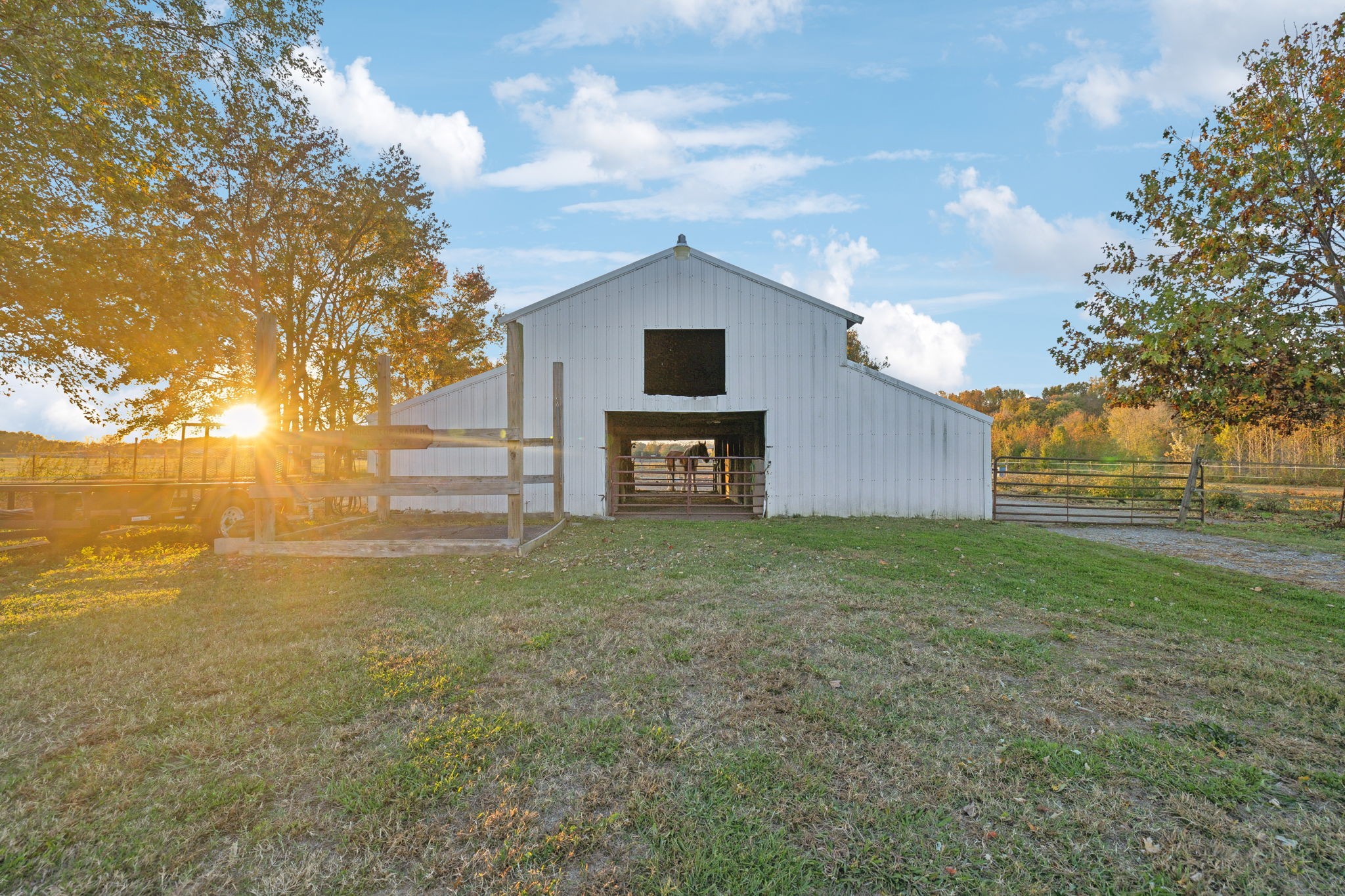 As the sun sets, casting a warm glow across the fields, horses graze peacefully under the soft light making the barn a true haven where passion for horsemanship thrives in harmony with nature’s beauty.