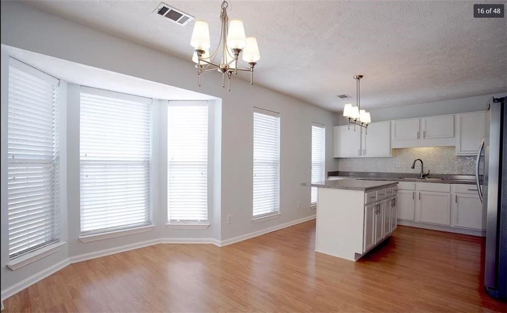 a large kitchen with cabinets wooden floor and stainless steel appliances