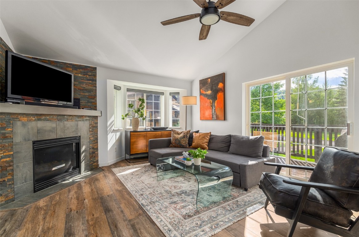 Living room featuring wood-type flooring, a fireplace, ceiling fan, and plenty of natural light