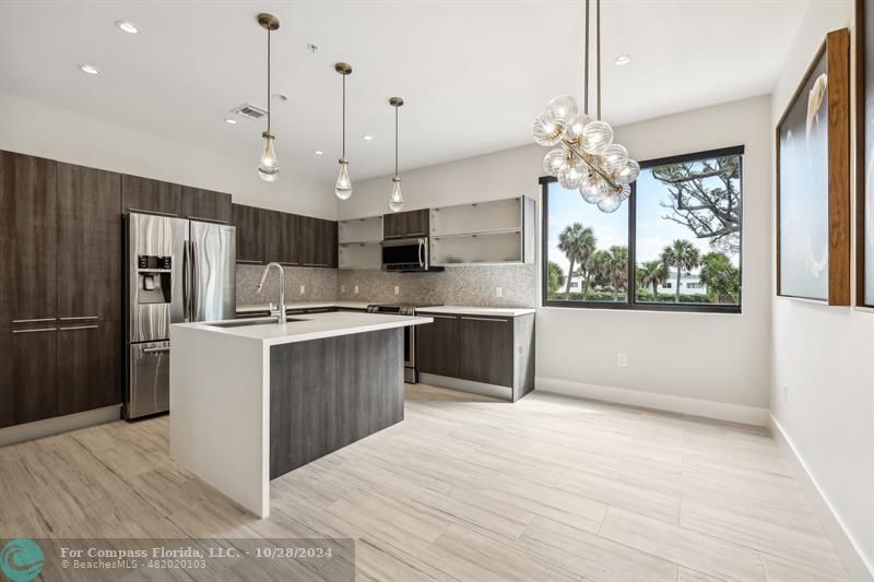 a large kitchen with kitchen island a large counter space a sink appliances and cabinets