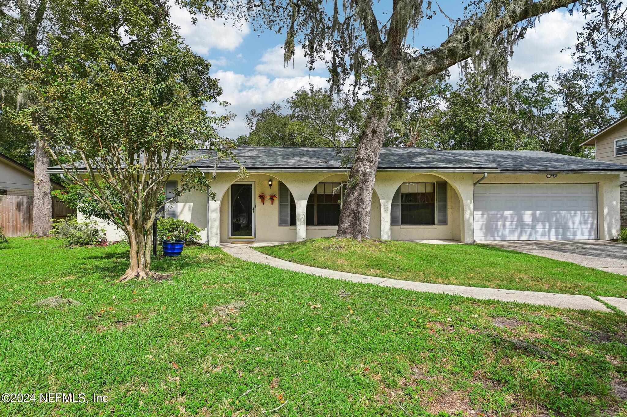 a view of a house with backyard and a tree