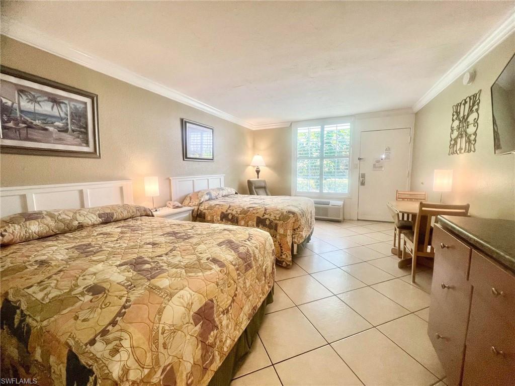 Bedroom with ornamental molding, light tile floors, and a wall mounted air conditioner