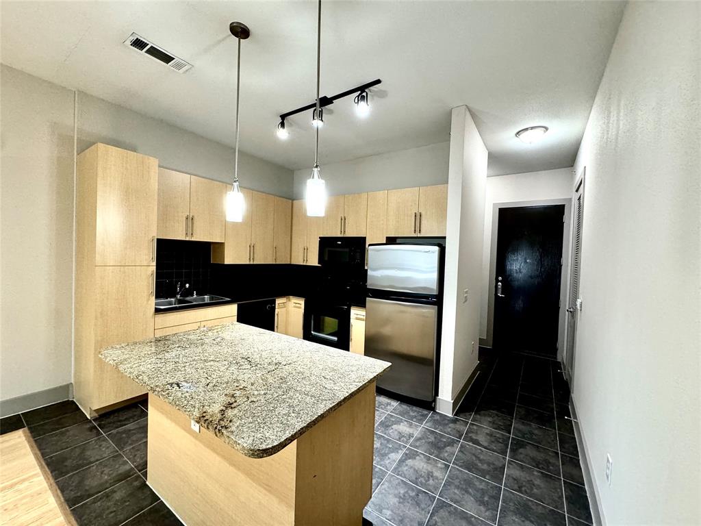 a kitchen with stainless steel appliances kitchen island granite countertop a refrigerator a stove top oven and a sink