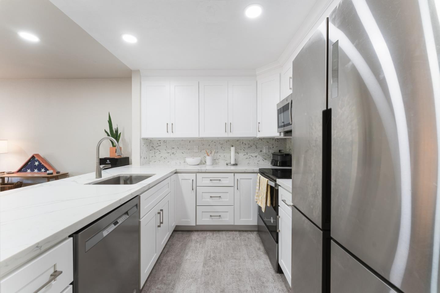 a kitchen with a sink a refrigerator and white cabinets