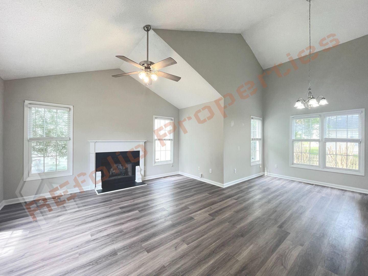 a view of empty room with wooden floor fireplace and a window