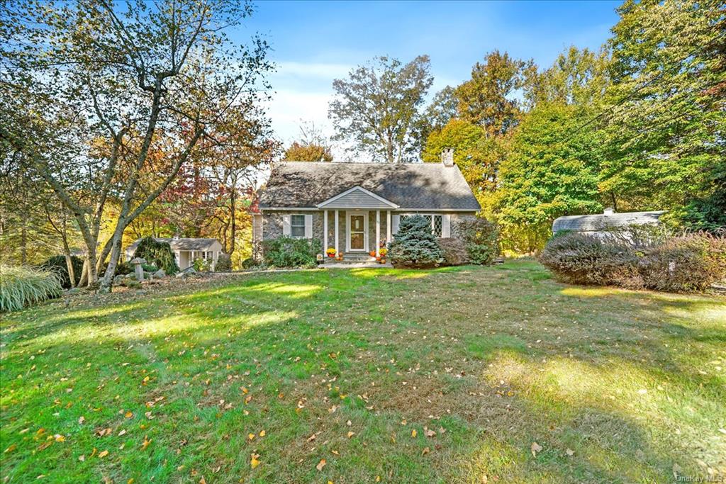 Stone Cape cod home with a front lawn