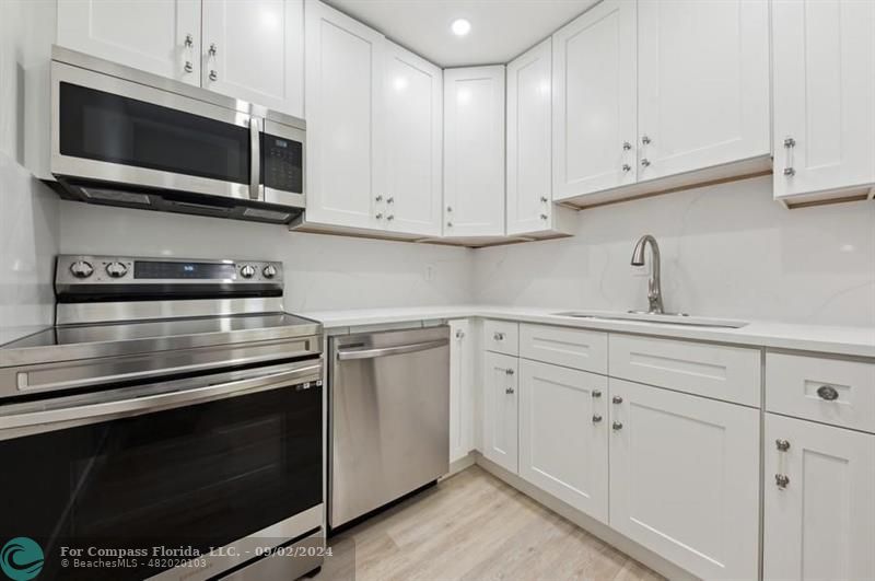 a kitchen with white cabinets stainless steel appliances and sink