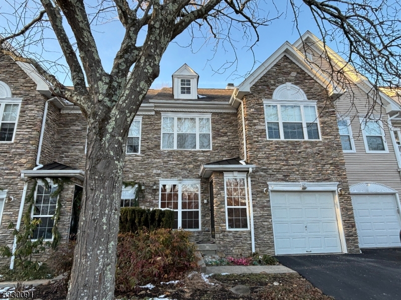 a front view of a house with a tree