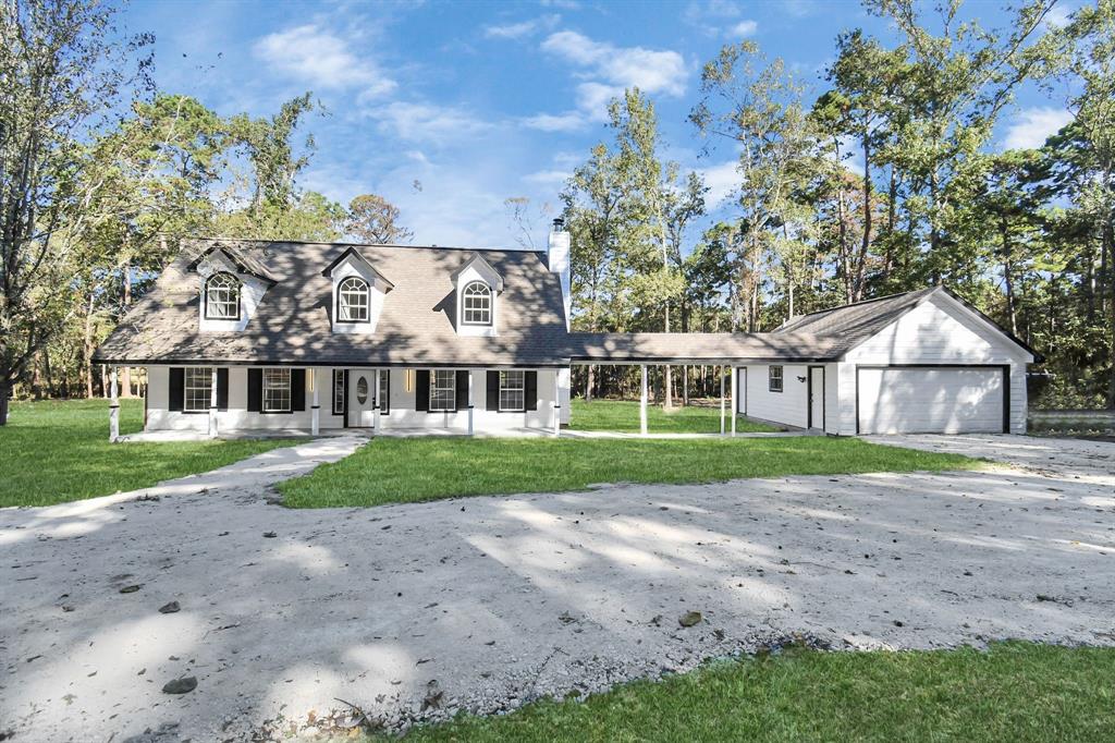 a view of house in front of a big yard with large trees