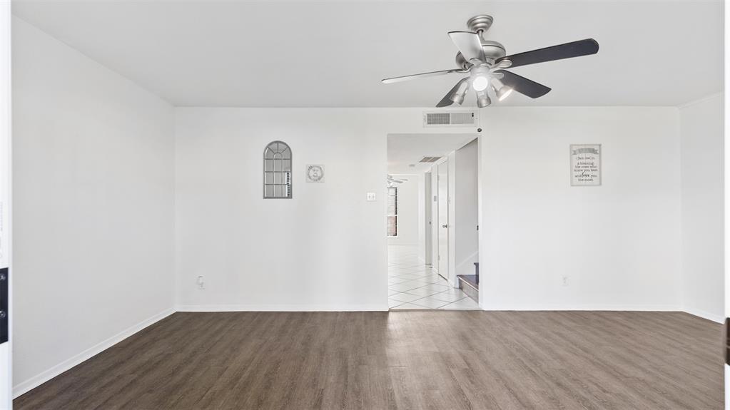 an empty room with wooden floor ceiling fan and windows