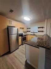 a kitchen with granite countertop a refrigerator and a stove top oven