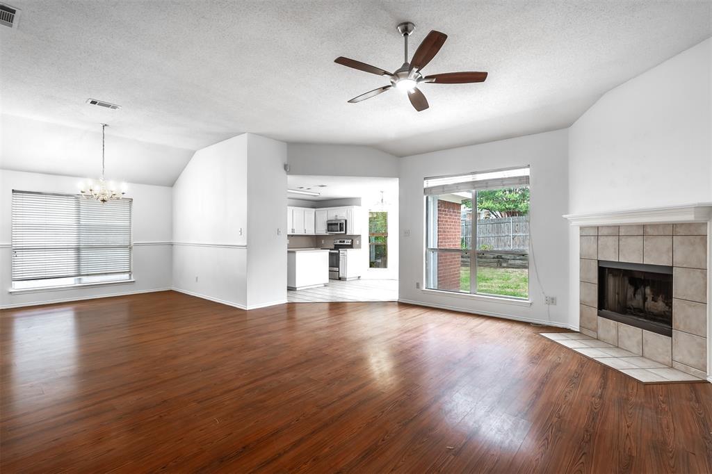 a view of a big room with wooden floor a ceiling fan and windows