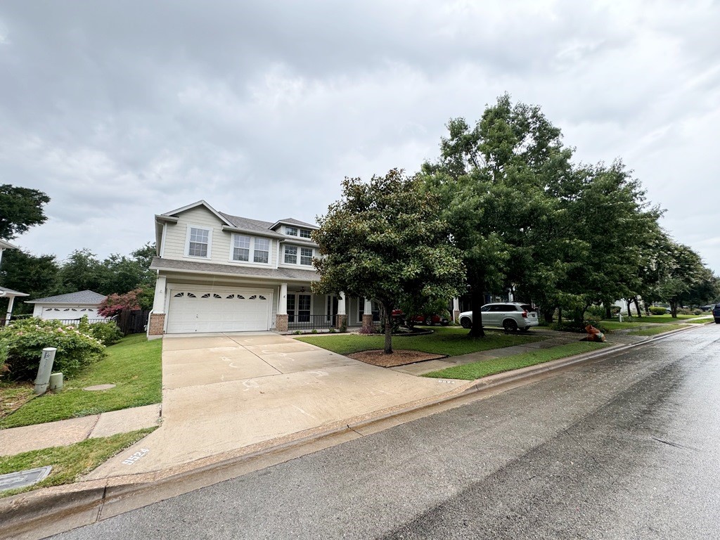 a view of a house with a yard and large trees