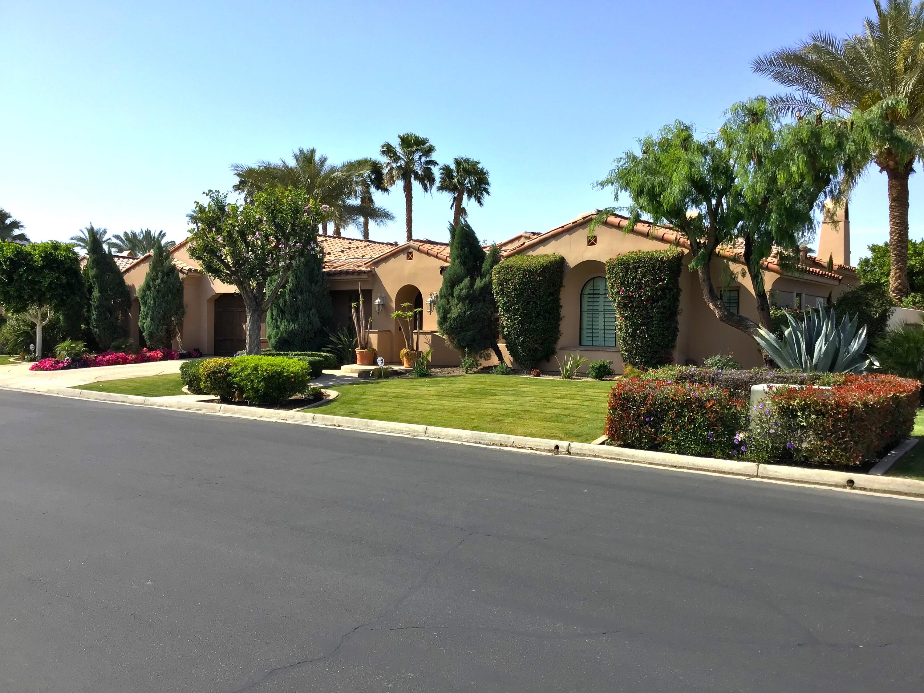 a view of a house with a yard and palm trees