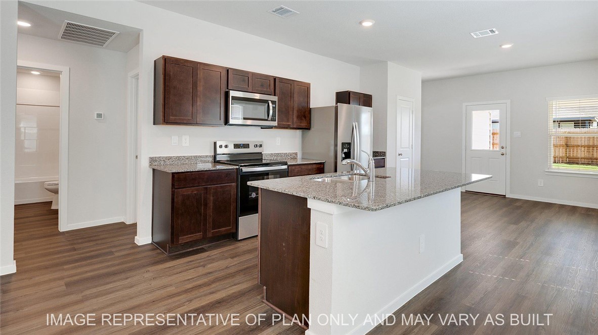 Kitchen featuring light stone counters, stainless