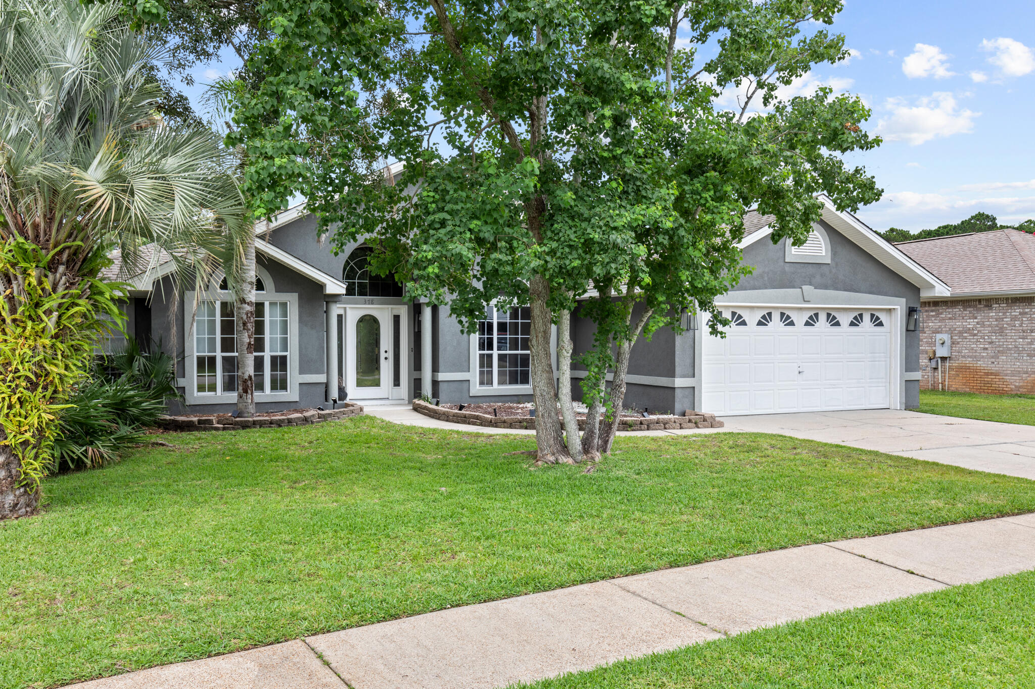 a front view of a house with a garden and trees