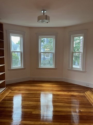 a view of an empty room with window and wooden floor