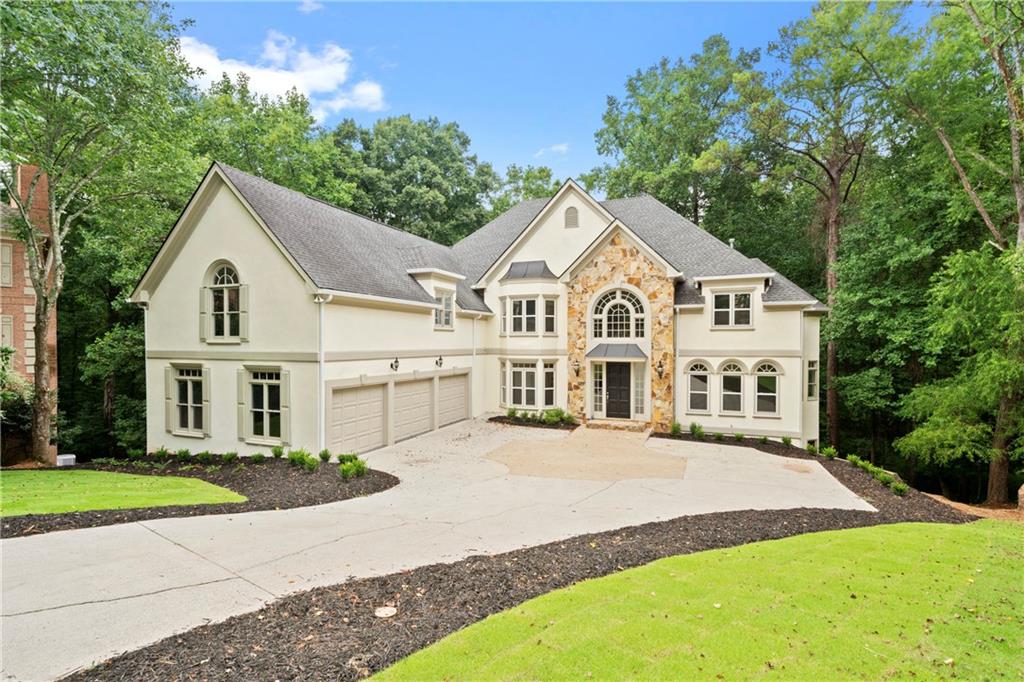 a view of house with a big yard and large trees