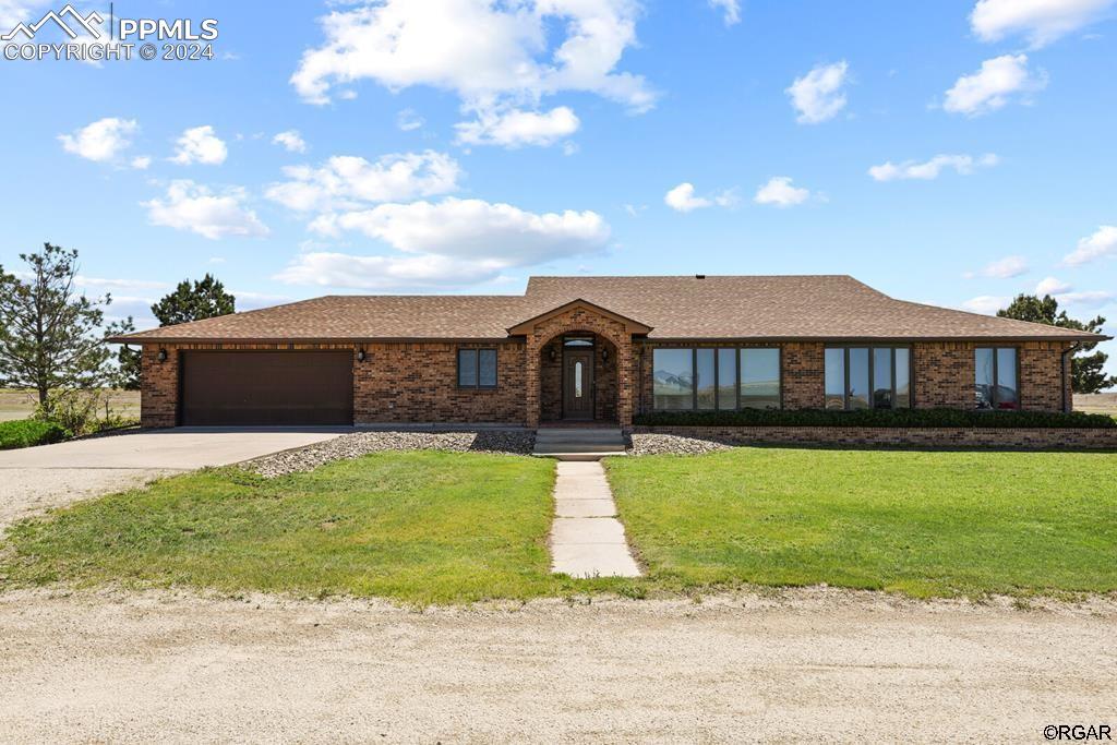 Single story home featuring a garage and a front lawn