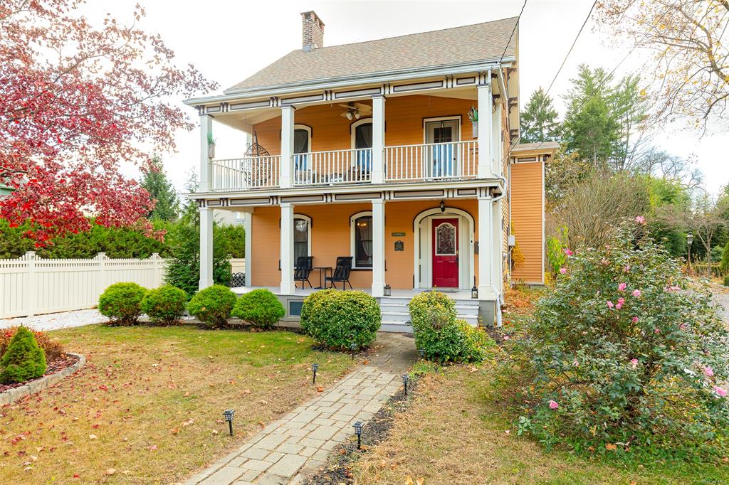 View of front of home featuring a front yard, covered porch, and a balcony