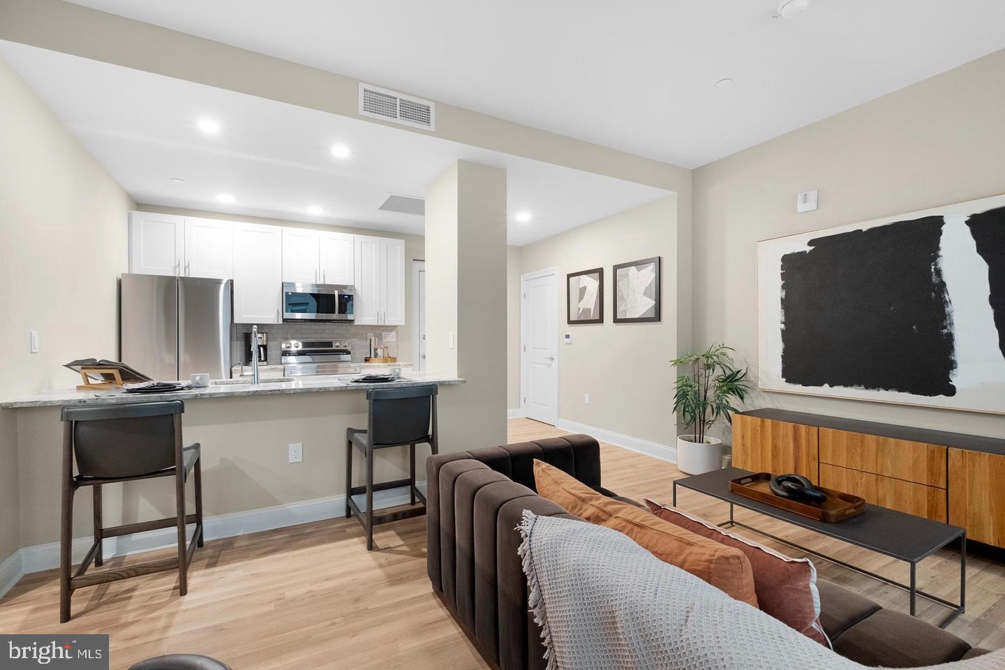 a living room with stainless steel appliances kitchen island granite countertop furniture and a flat screen tv