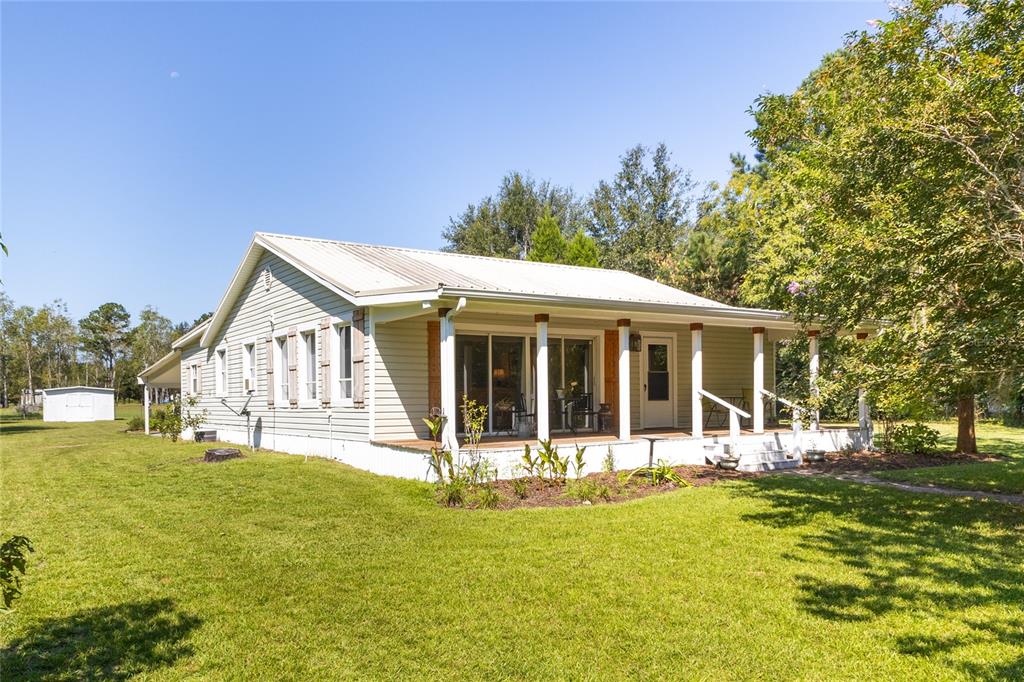 a view of a house with a big yard and large trees