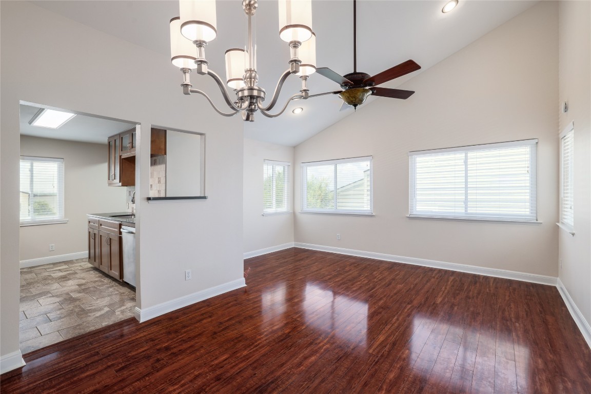 a view of a room with wooden floor ceiling fan and windows