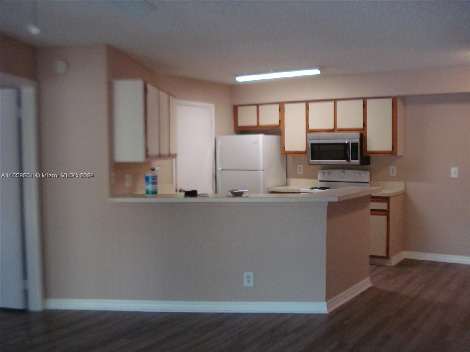 a view of kitchen with wooden floor and electronic appliances