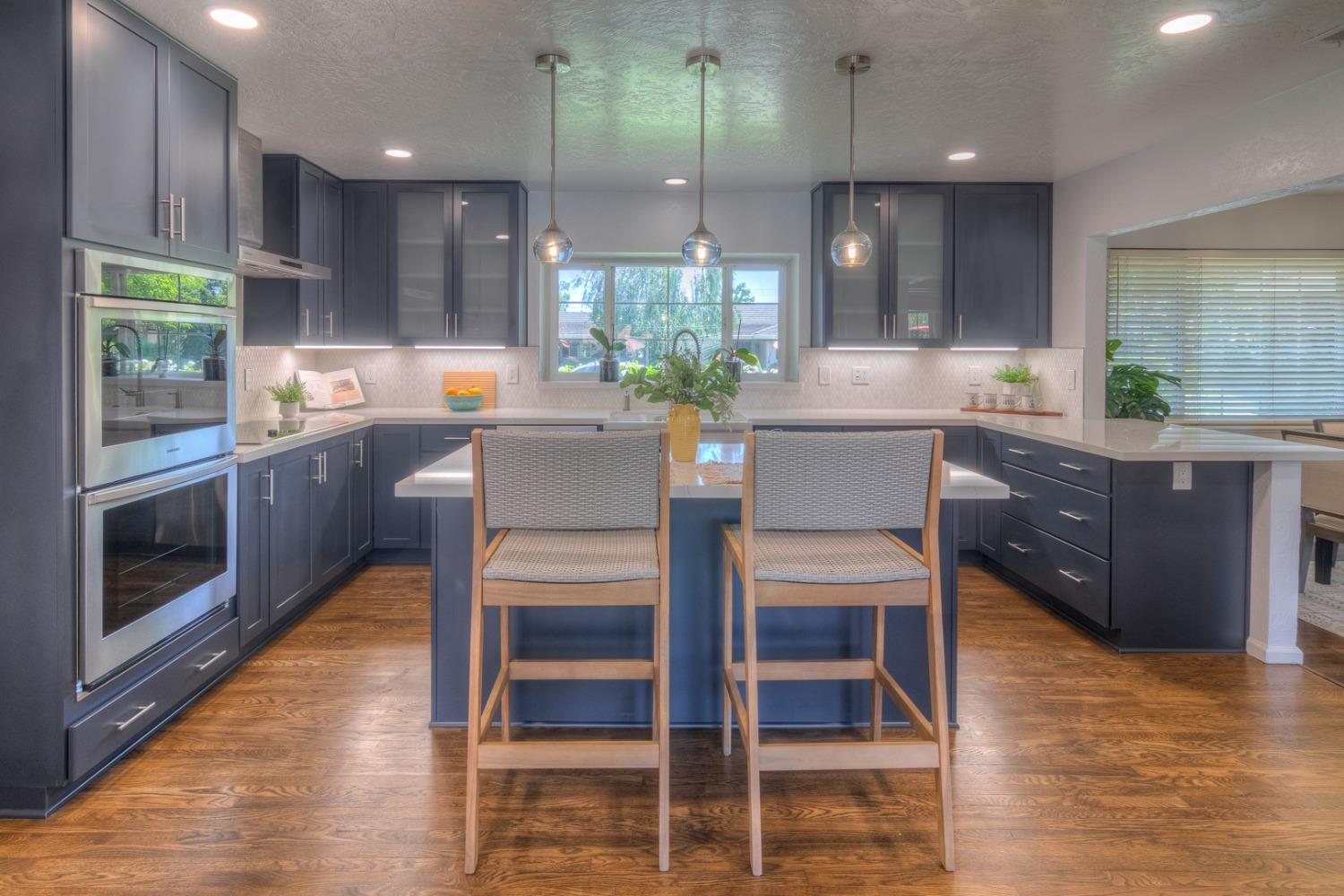 a kitchen with stainless steel appliances kitchen island granite countertop a table chairs sink and cabinets