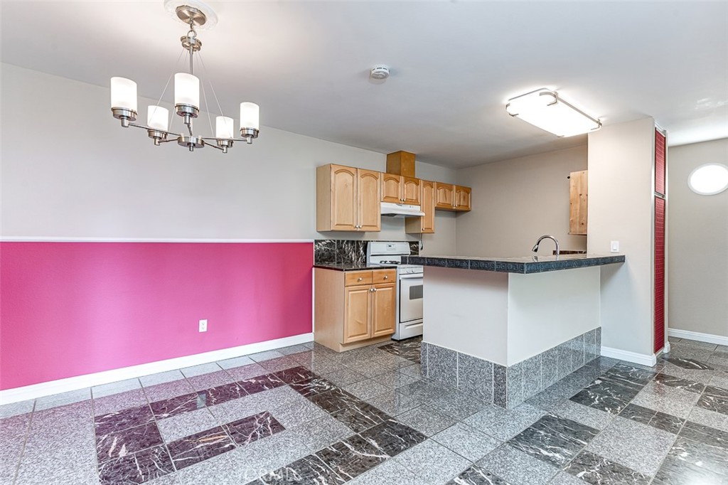 a kitchen with a stove a refrigerator and chandelier