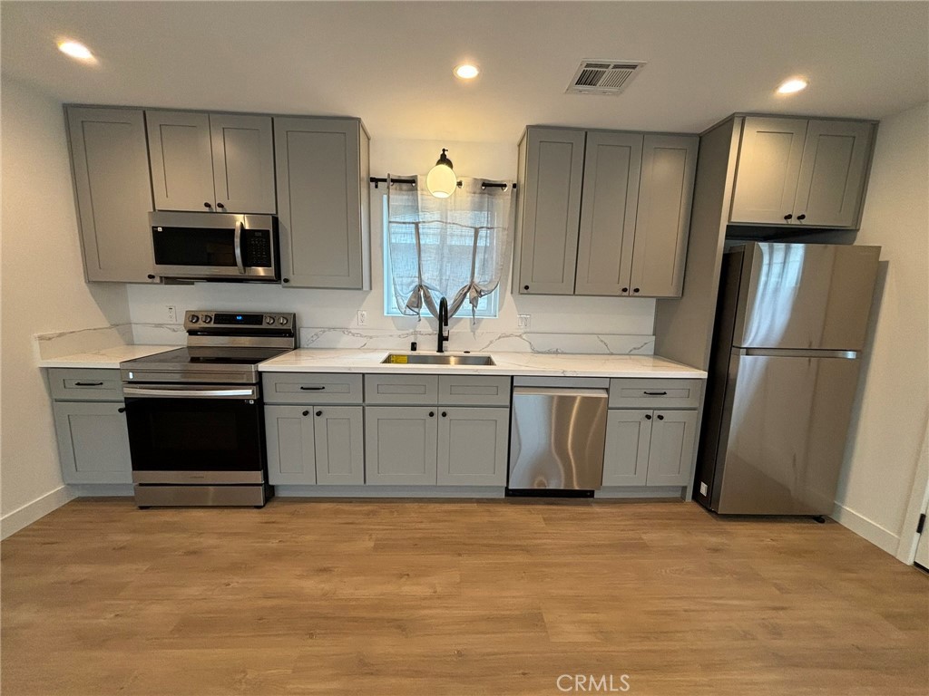 a kitchen with stainless steel appliances a stove a sink and a refrigerator