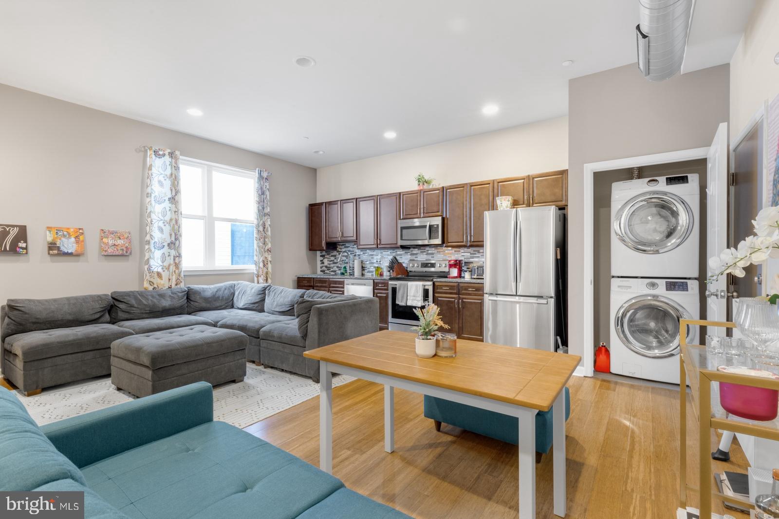 a living room with furniture a clock and kitchen view