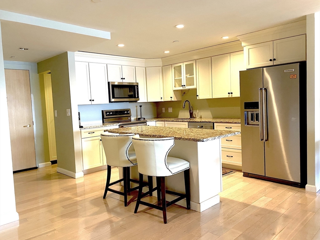 a kitchen with stainless steel appliances granite countertop a stove a refrigerator a sink a dining table and chairs