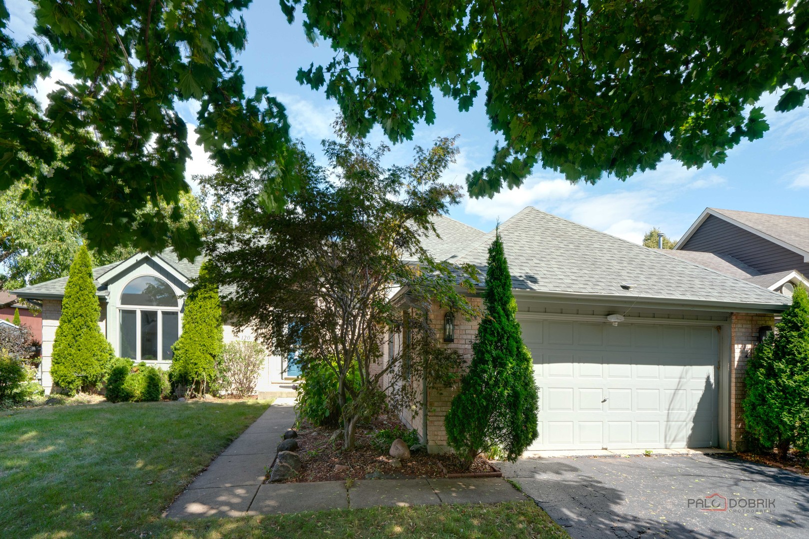 a front view of a house with a garden and trees